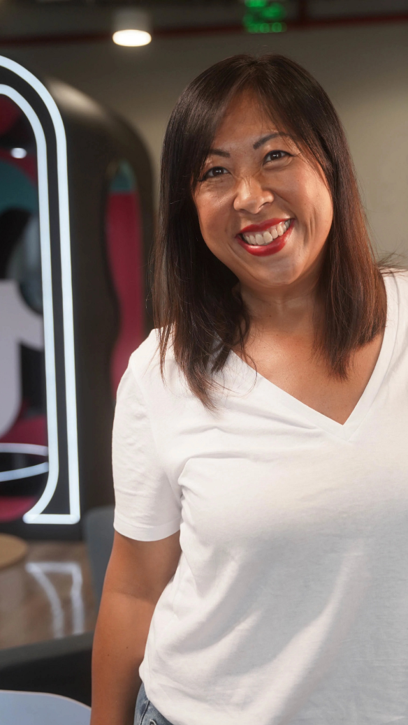 A female Asian TikTok employee smiles as she poses for a photo.