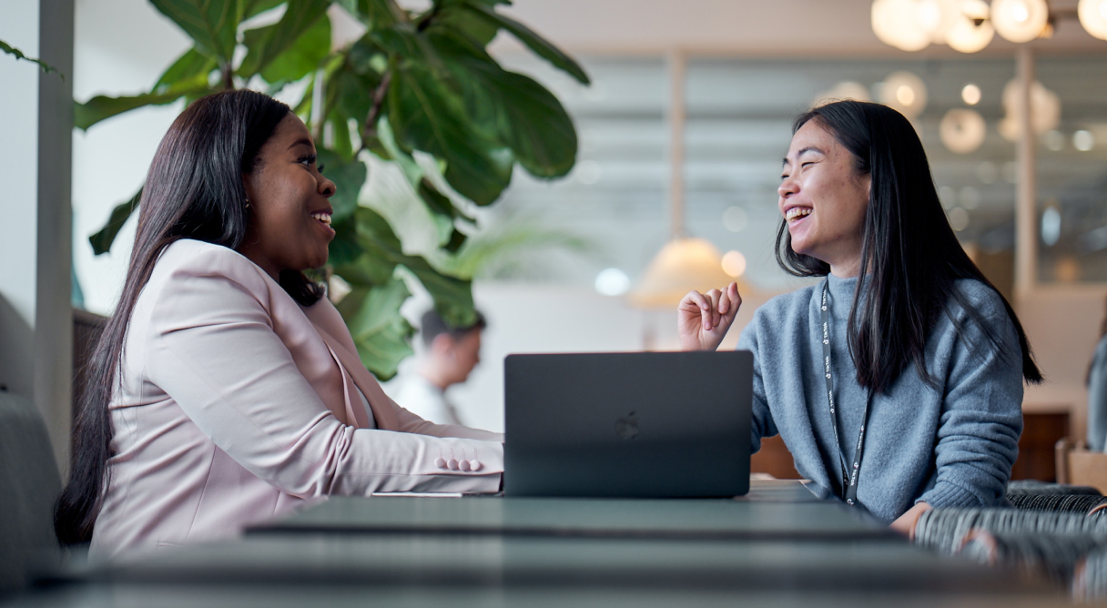 Two TikTok MBA graduates having a discussion at the office in front of their laptop.