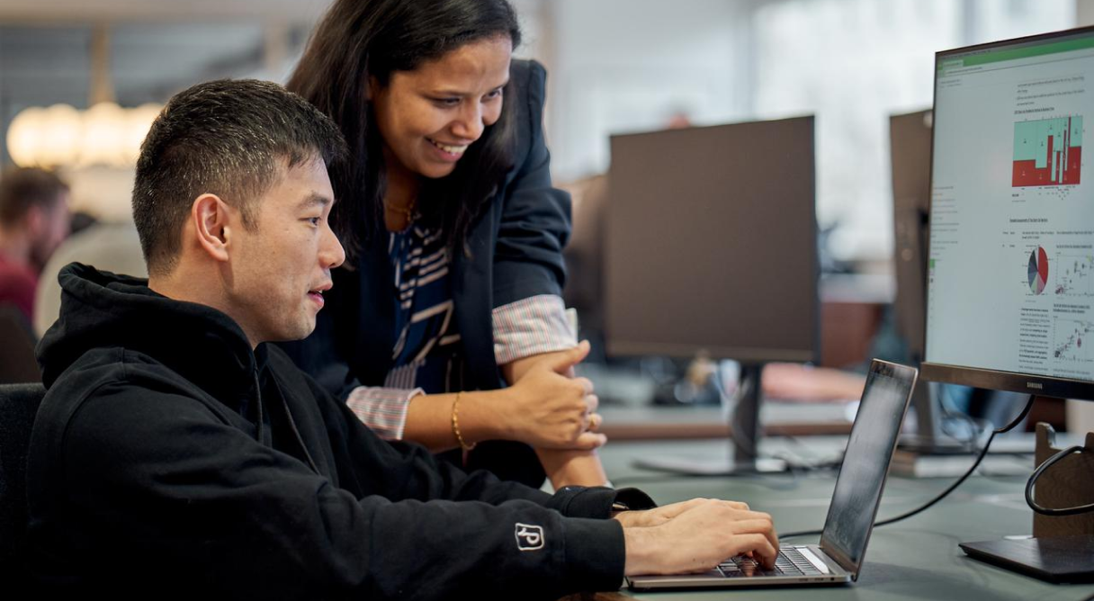 Two TikTok PhD students work together at a computer.